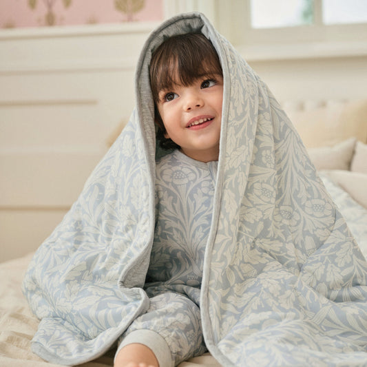 Child wearing Acorn Slate Blue cozy blanket over head, lifestyle