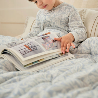 Child wrapped in Acorn Slate Blue cozy blanket reading, lifestyle