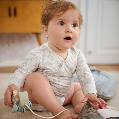Baby wearing Acorn Slate Blue kimono onesie, playing with toys
